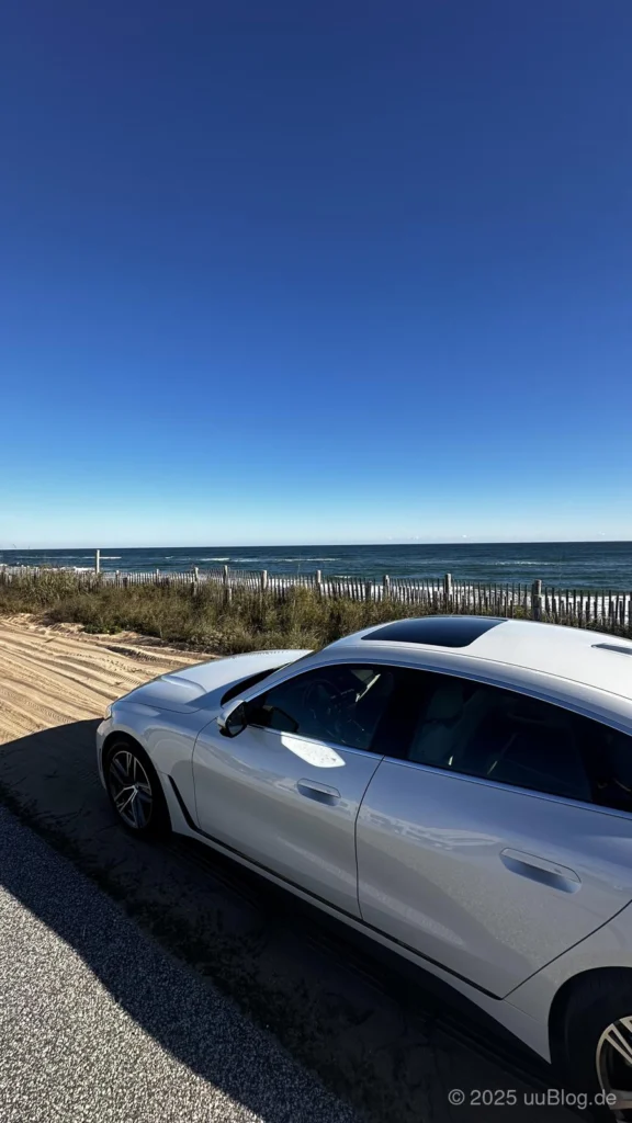Weißes Auto geparkt neben einem Sandstrand entlang des A1A Scenic Highway mit Meerblick bei strahlend blauem Himmel in Ormond-by-the-Sea, Florida.
