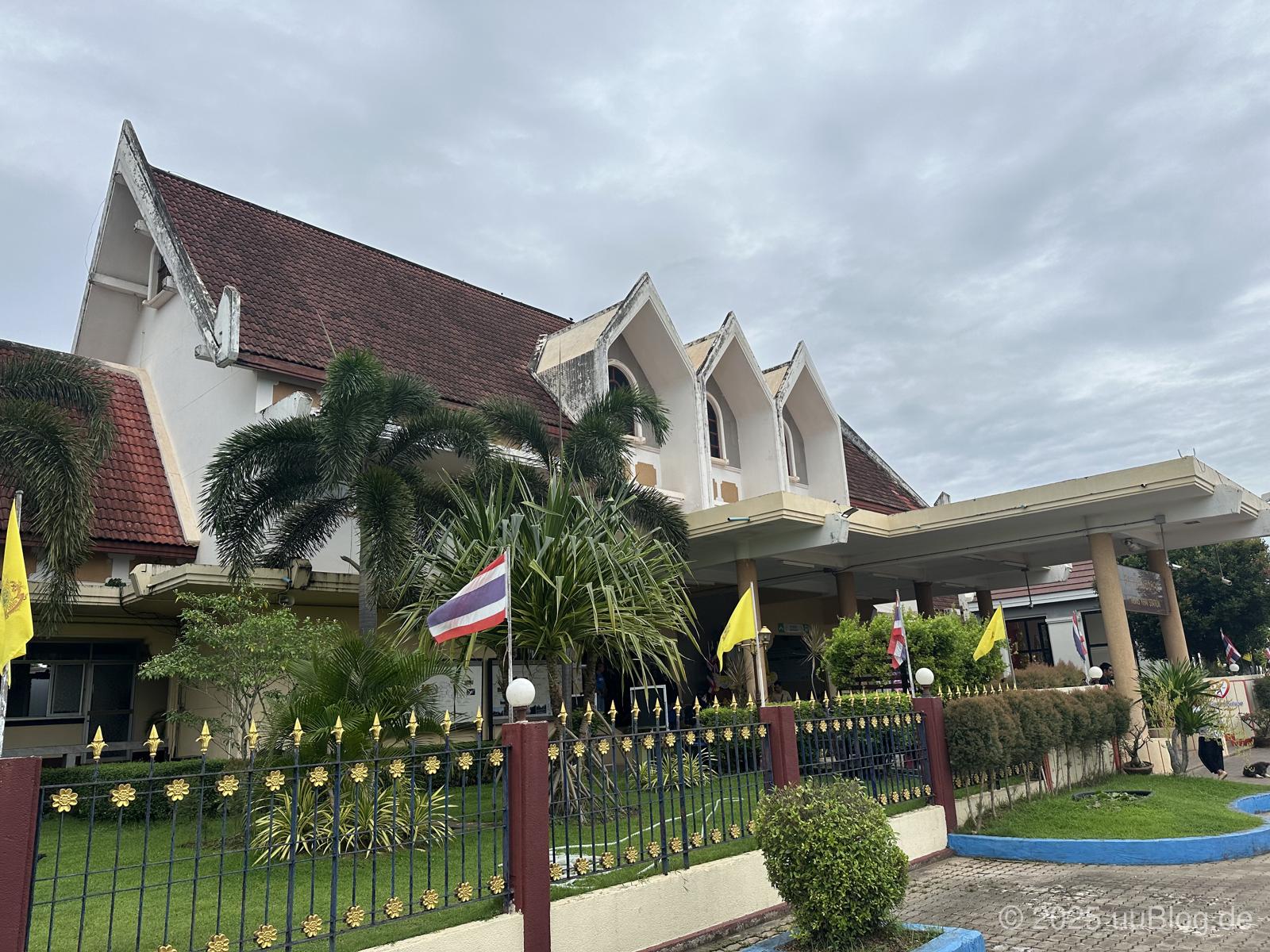 Eingang eines Bahnhofs mit charakteristischen spitzen Dächern und thailändischen Flaggen in Nong Khai, Thailand.