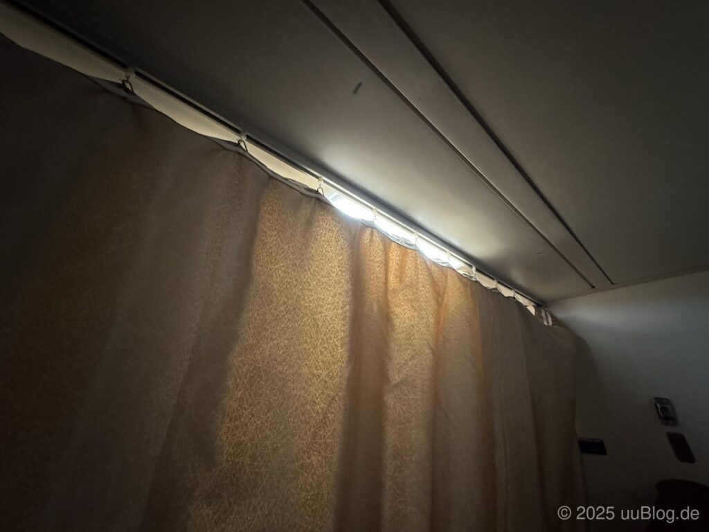 Blick auf eine Gardine in einem Nachtzugabteil, durch die Licht schimmert.